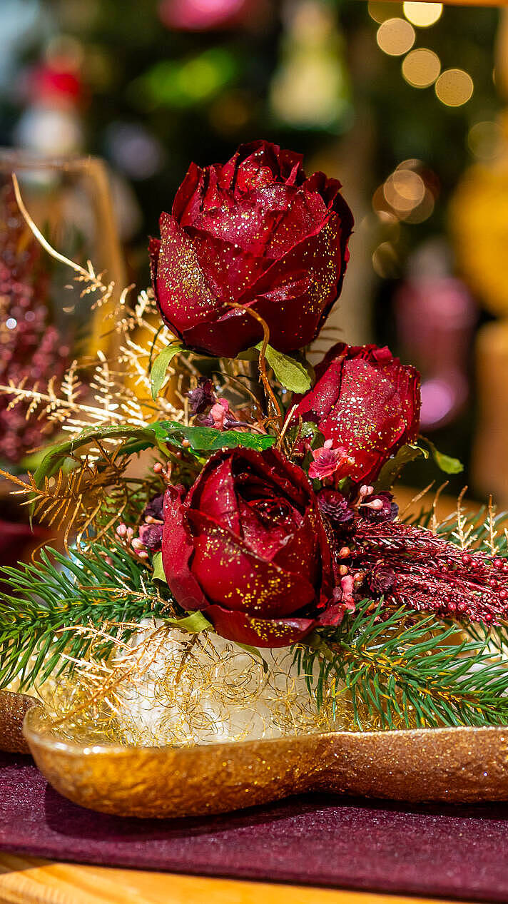 Festliche Weihnachtsdekoration mit roten Rosen, goldenen Akzenten und Tannengrün im JOSKA Glasparadies in Bodenmais.