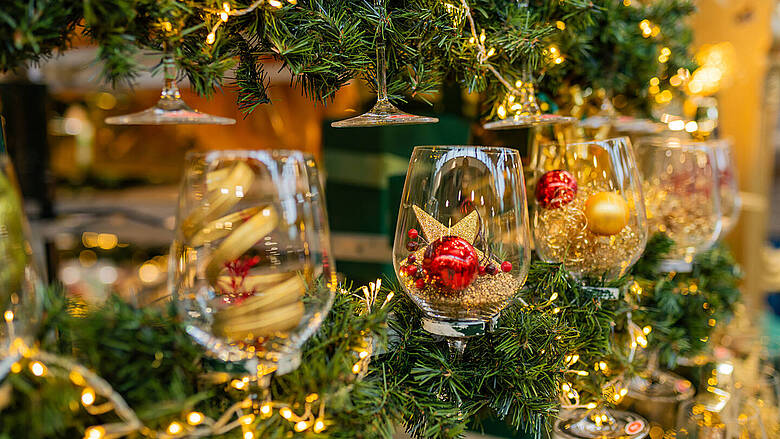 Dekorativ gefüllte Weingläser mit Kugeln und Sternen als kreative Weihnachtsdekoration im JOSKA Glasparadies.