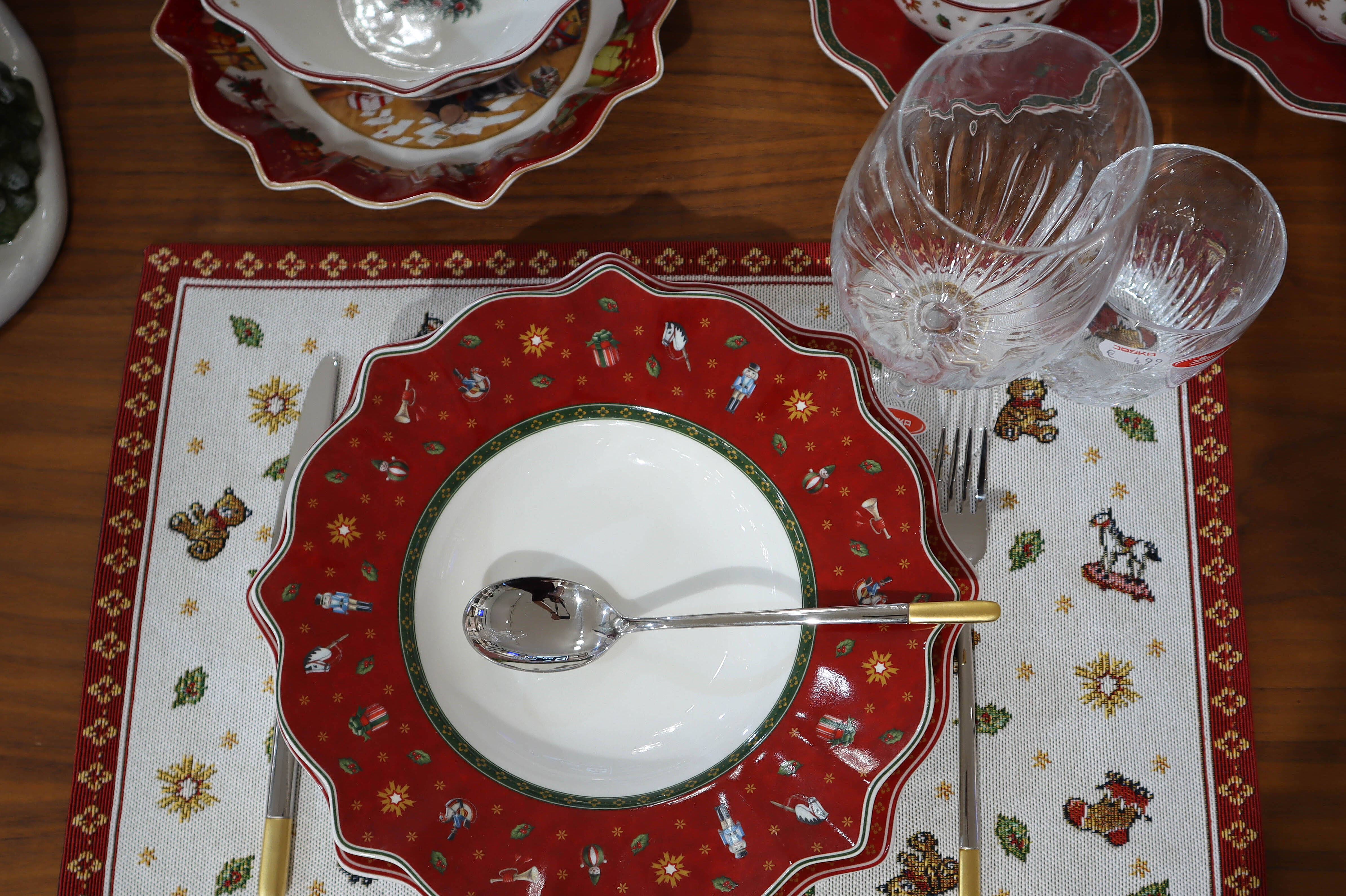 Festlich gedeckter Tisch mit Villeroy & Boch Weihnachtsgeschirr aus der Serie Toys Delight – elegante Tischdekoration mit roten Tellern, Glaswaren und goldenen Akzenten.