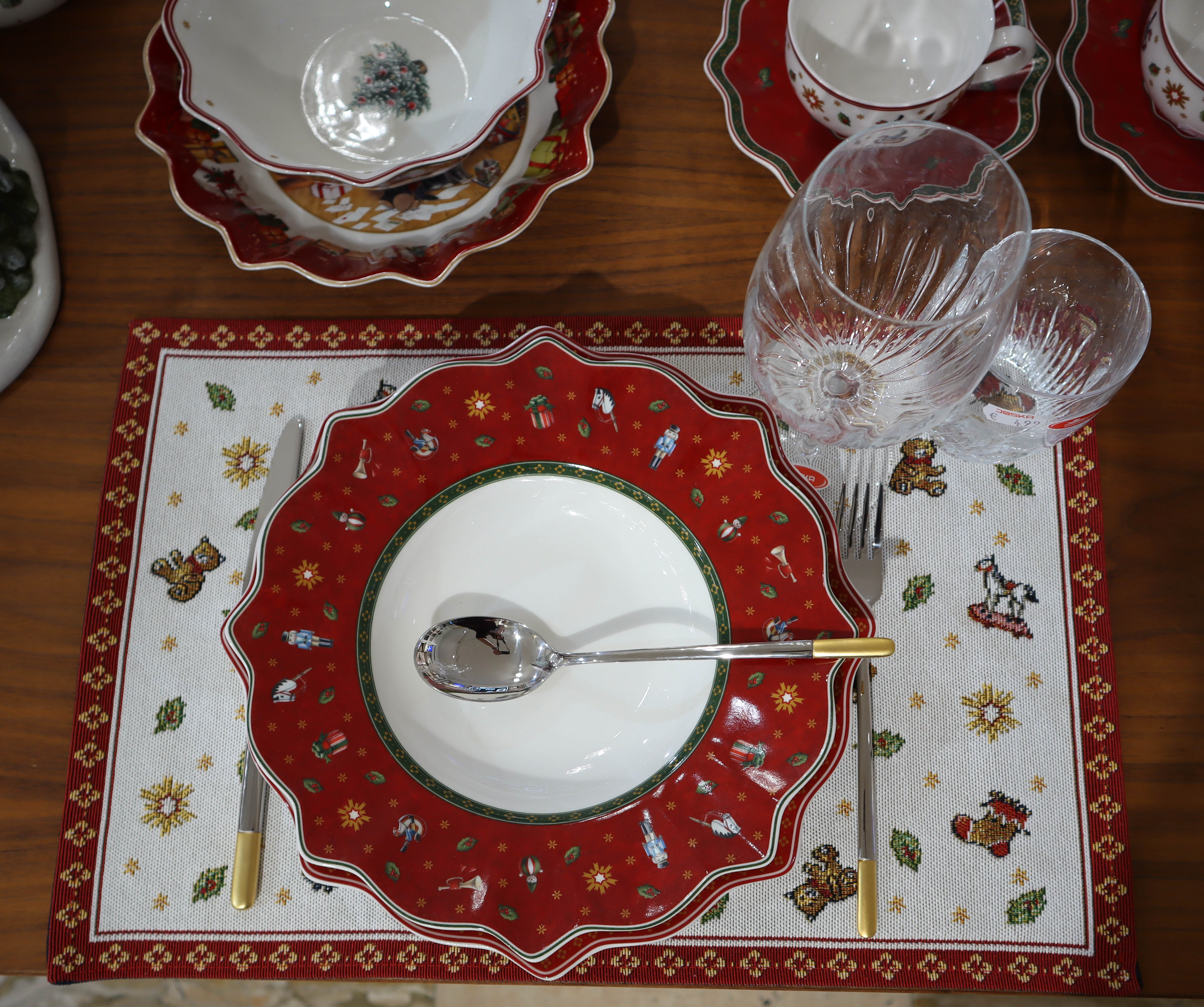 Festlich gedeckter Tisch mit Villeroy & Boch Weihnachtsgeschirr aus der Serie Toys Delight – elegante Tischdekoration mit roten Tellern, Glaswaren und goldenen Akzenten.
