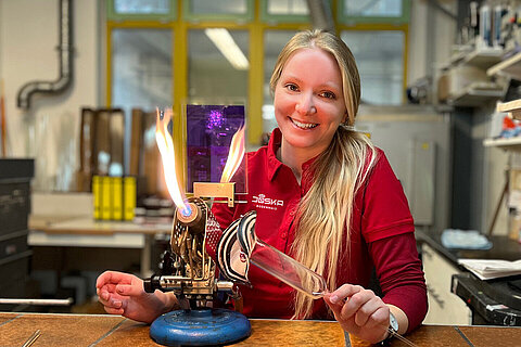 Kunstglasbläserin bearbeitet ein Glasröhrchen mit offener Flamme im JOSKA Glasparadies.