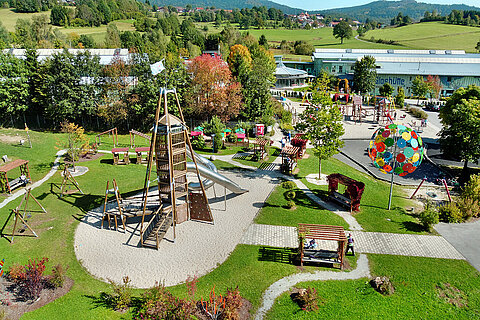 Luftbildaufnahme des JOSKA Kinderlandes in Bodenmais mit Spielplatz, Holzgeräten und Sitzgelegenheiten.