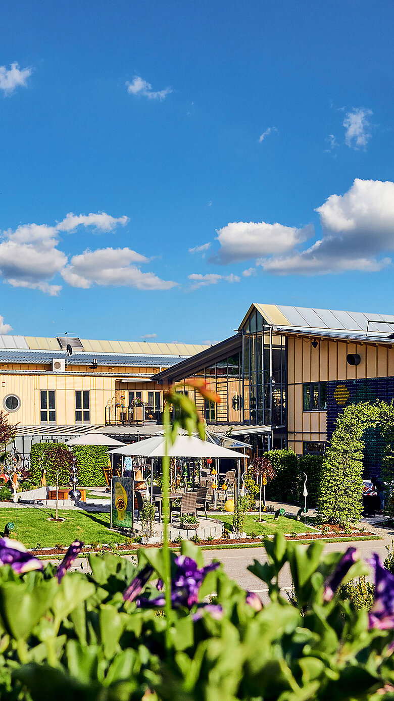 Blick auf das JOSKA Glasparadies in Bodenmais mit Gartenpavillon und blühenden Beeten